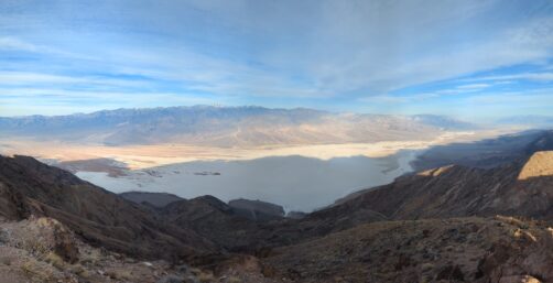 View down a rocky hill to sand below and rocky hills in the distance